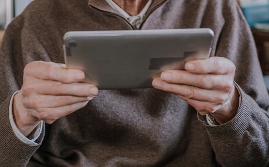 senior qui tient dans ses mains une tablette