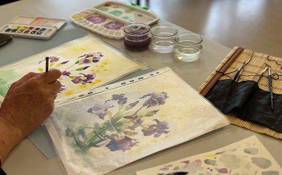 main femme qui peint avec de l'aquarelle une fleur polyèdre seynod annecy