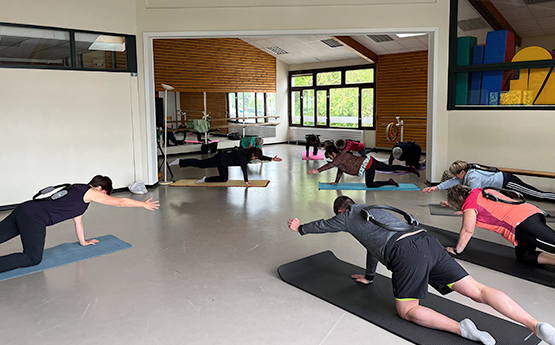 personnes sur tapis en position pilates avec bras en l'air polyèdre seynod annecy