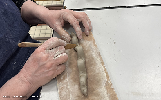 main qui sculpte une chenille en poterie polyèdre seynod annecy