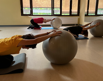 femmes en position assisse sur les genoux et bras tendu sur ballon pilates polyèdre seynod annecy