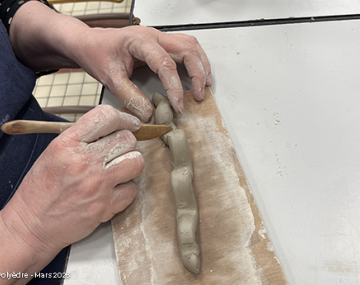 main qui sculpte une chenille en poterie polyèdre seynod annecy